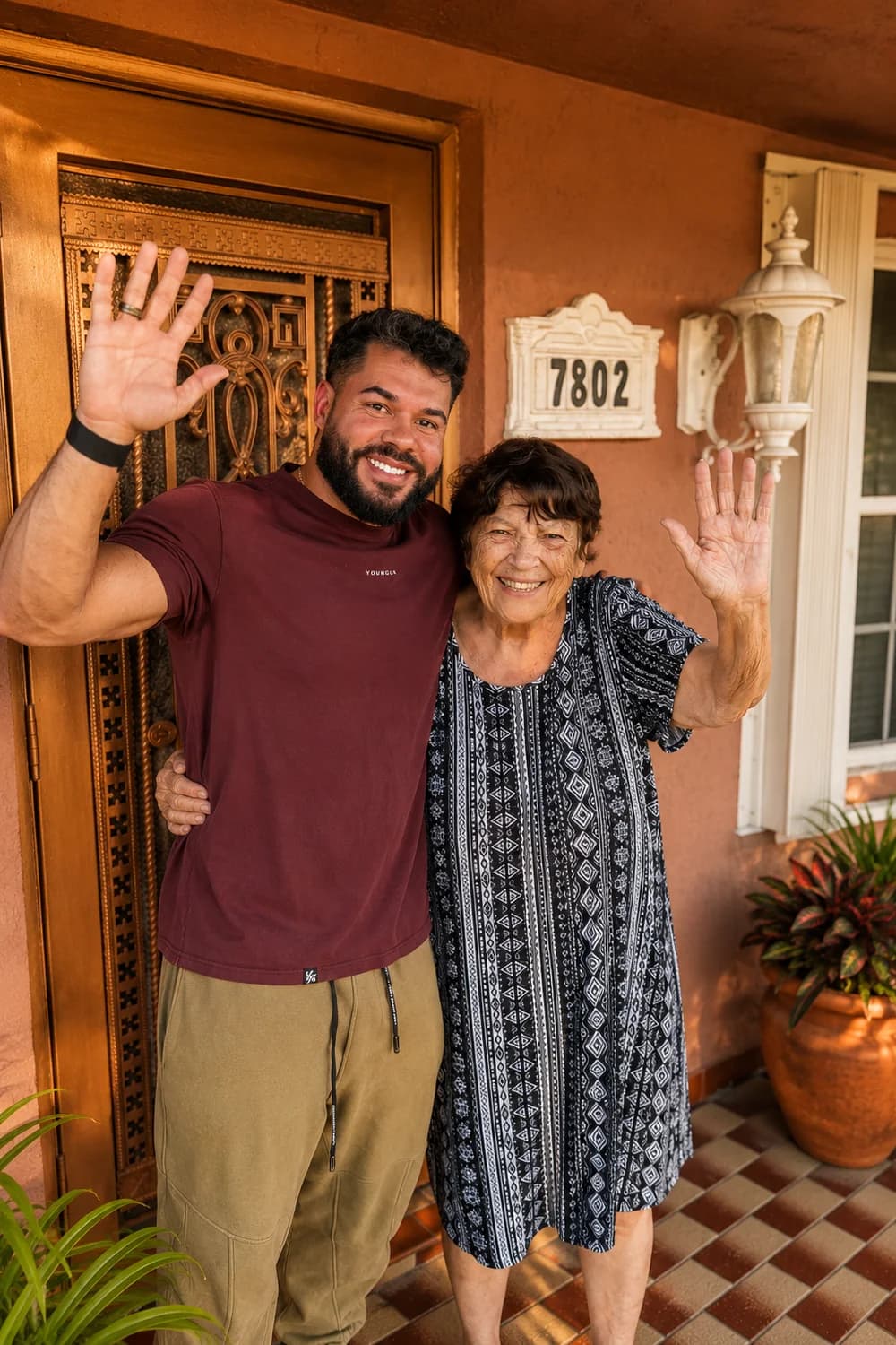 Albie, TrueHeart's founder, and an older woman waving and smiling together on her South Florida front porch.